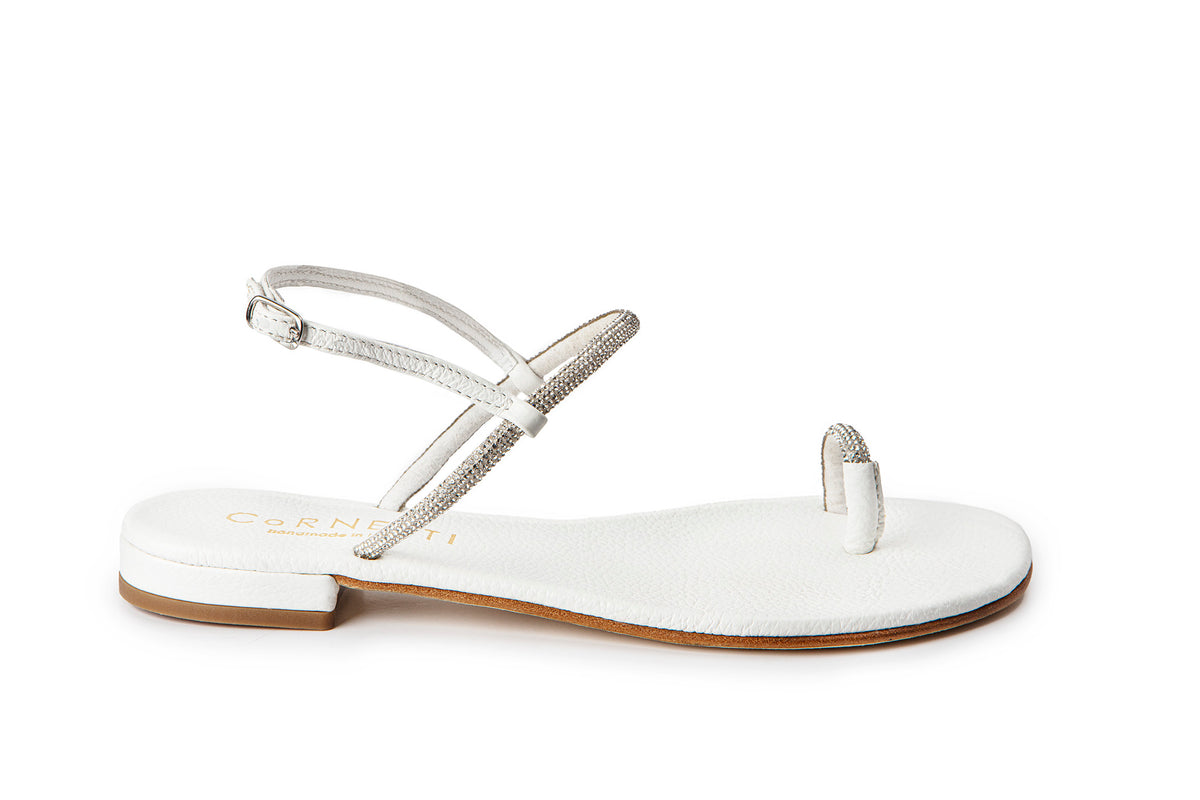 Side view of Sardinia sandal in white showcasing rhinestone-studded straps, toe loop, low stacked heel on white background