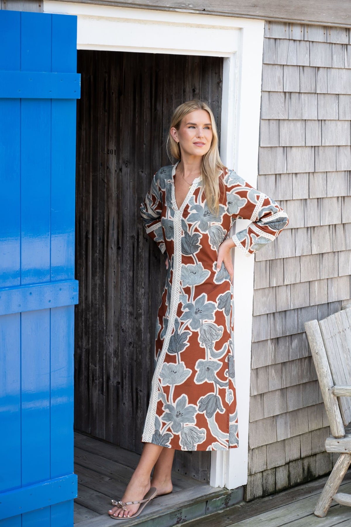Front view of Bardot Merrain in Coco showcasing floral print, cotton lace trim, V-neck, and three-quarter sleeves by a blue door