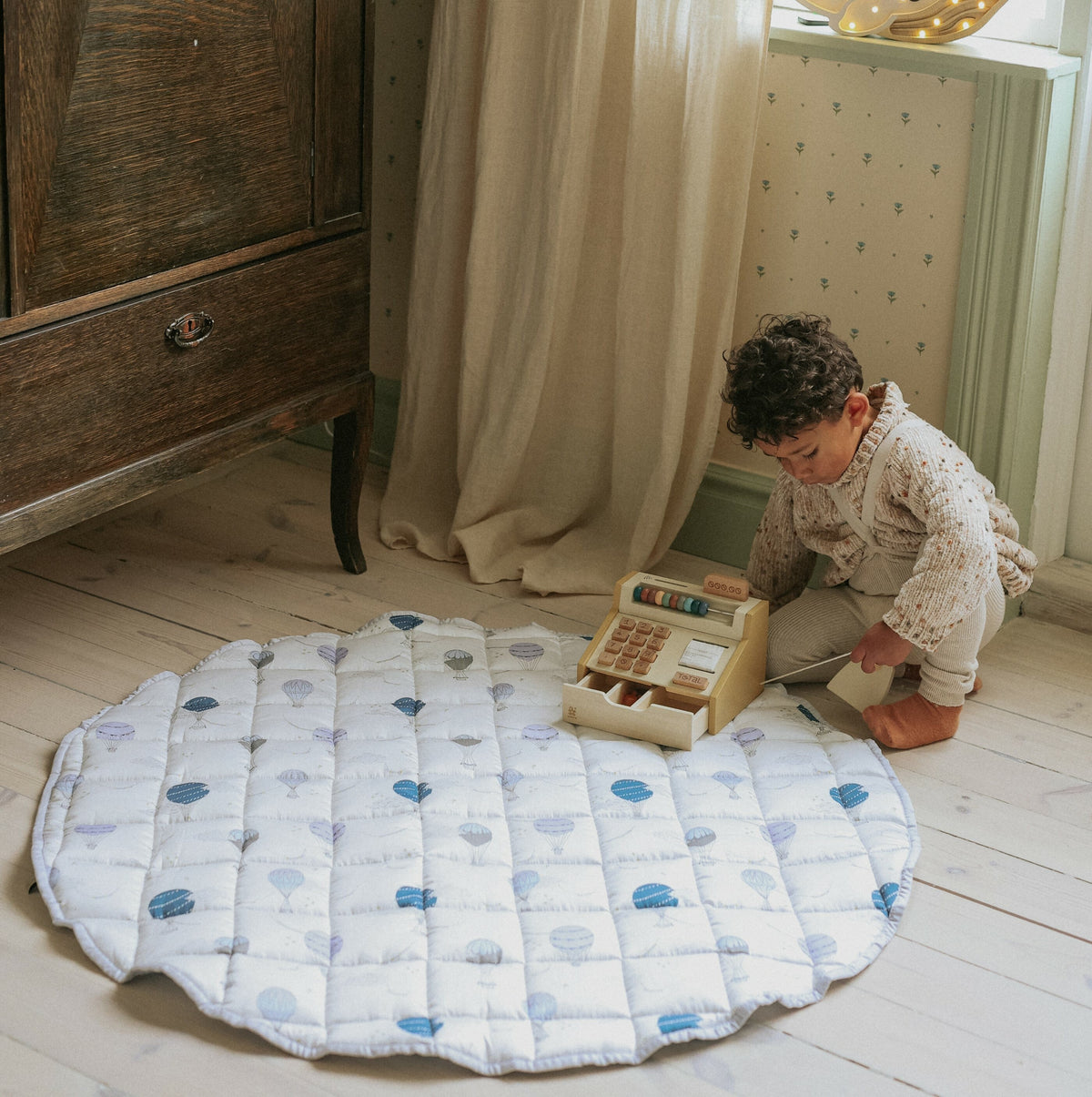 Touch the sky play mat in blue. Child is playing on play mat with wooden toy cash register