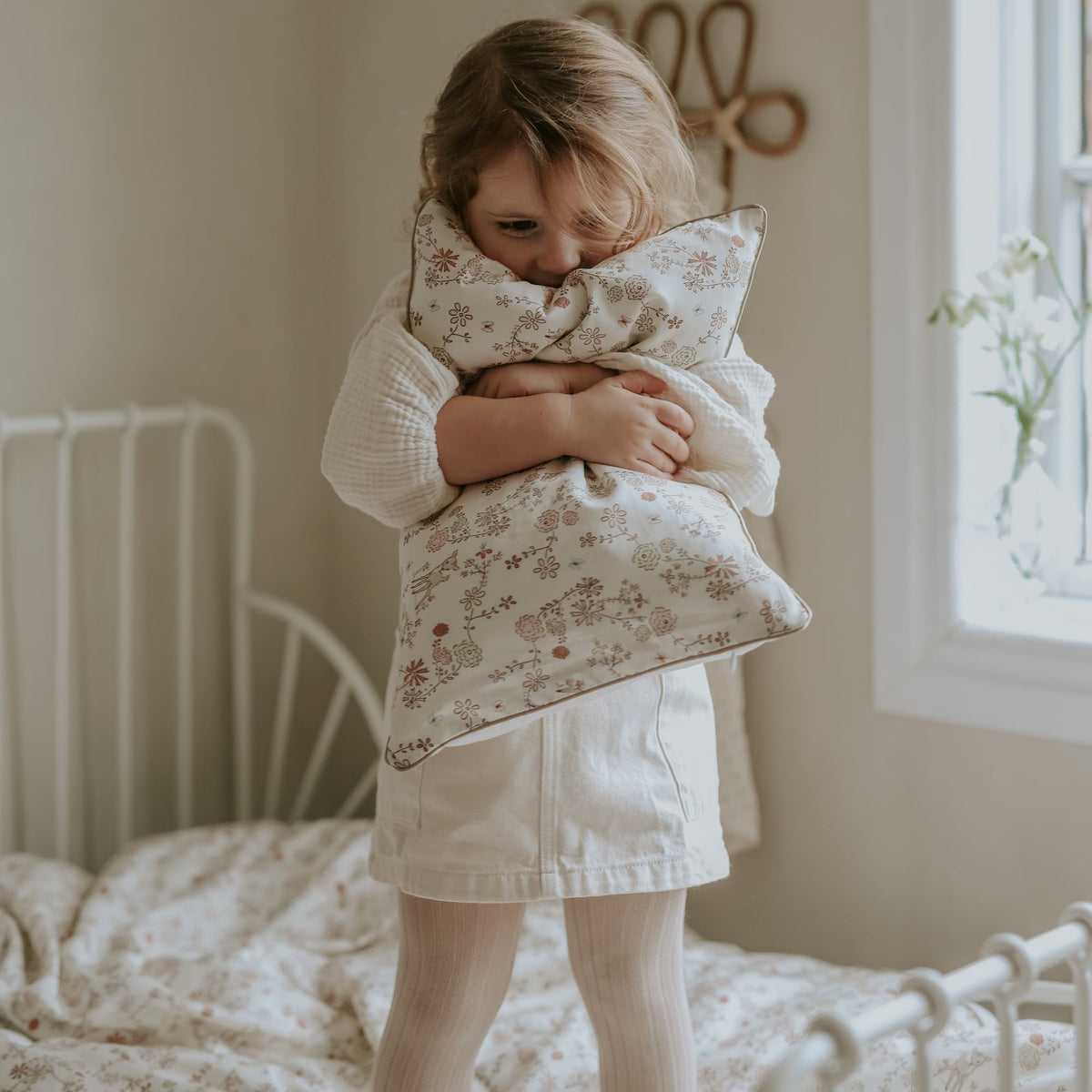 Toddler hugging a gooselings toddler pillow in the print "Into The Woodlands" in color ivory
