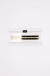 The Bella Rosa Collection Mia Acrylic Clutch with Ivory Satin Zipper Pouch with a harmonica inside against a white background.
