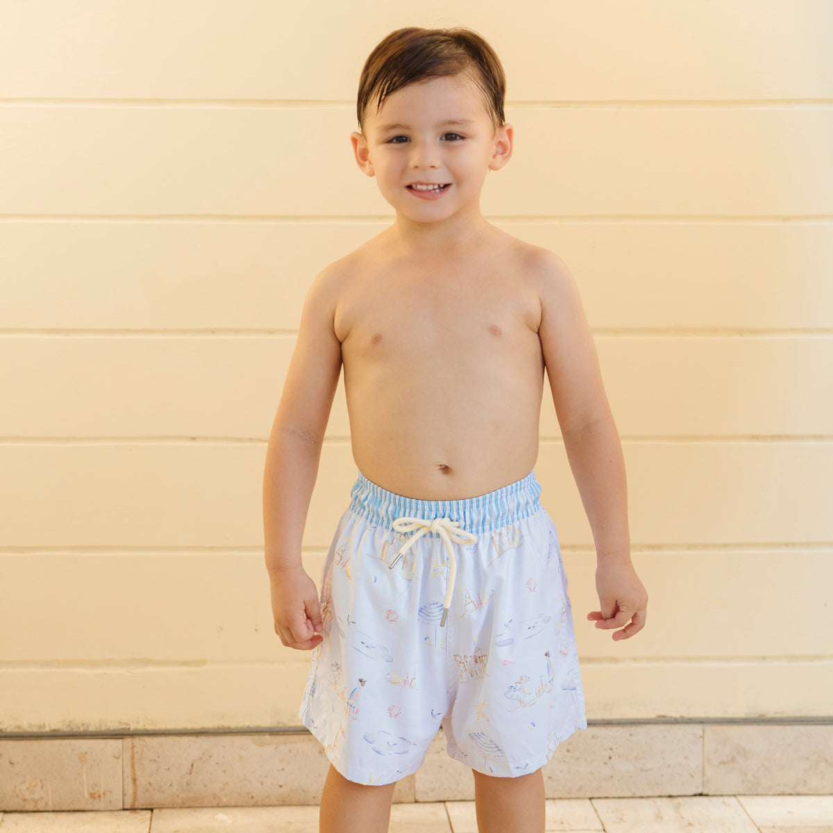 Front view of Kyle Boy swim trunks in Seaside on a model with elastic waistband, drawstring and pastel seaside print