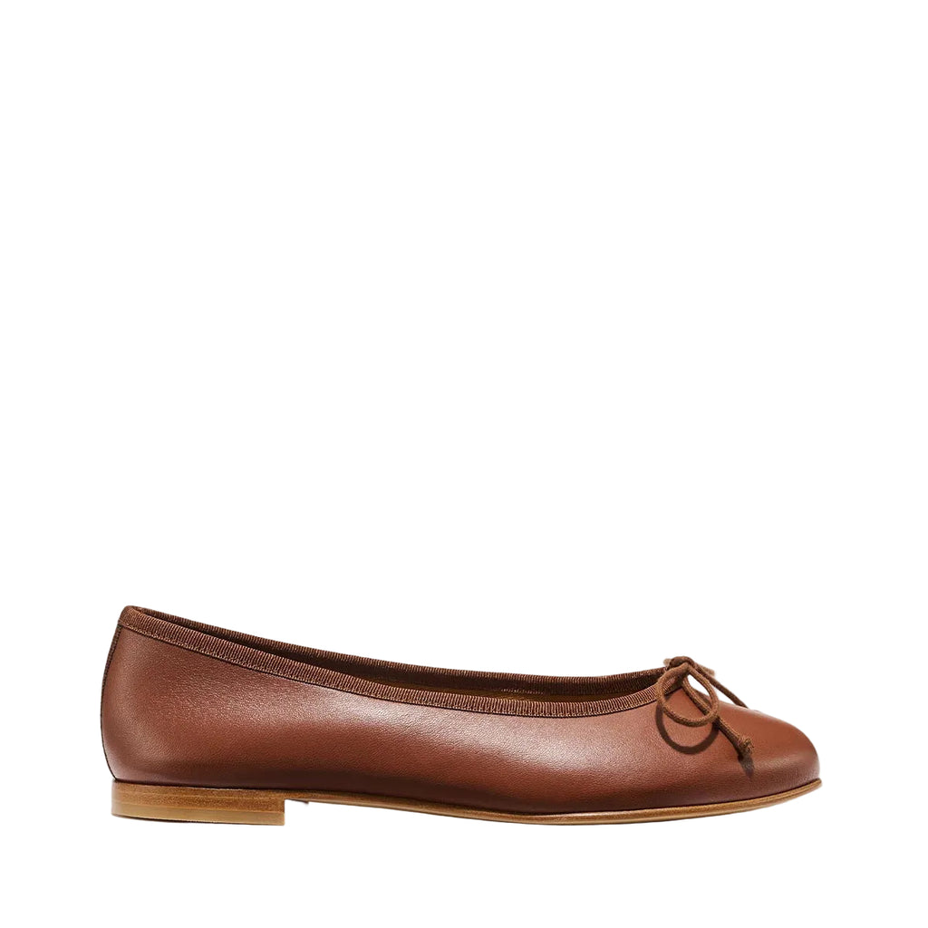 The Demi - Cognac Nappa by margaux-development is a brown leather ballet flat handmade in Spain, featuring a small bow, low wooden heel, and rounded toe, displayed on a plain light background.