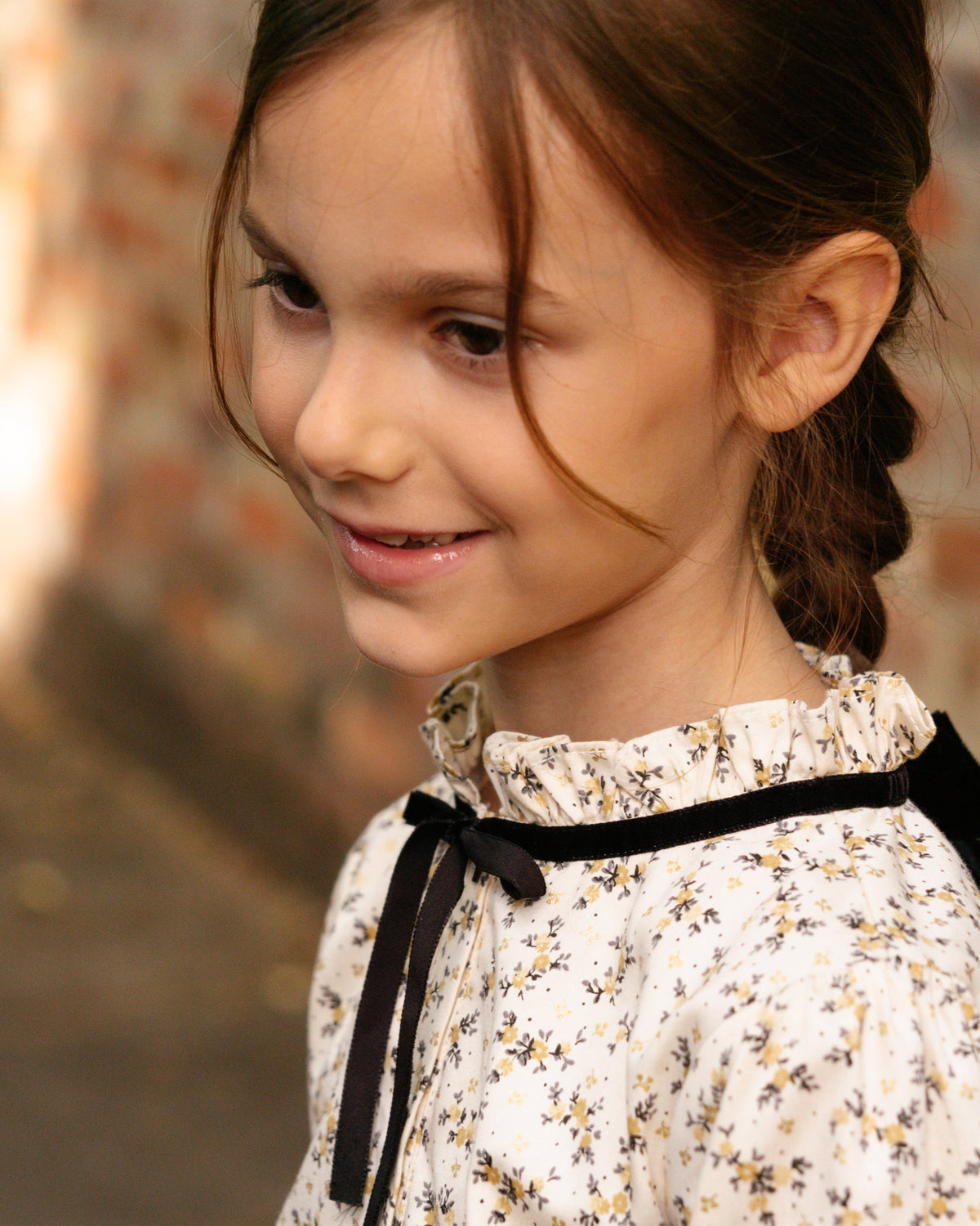 Young girl with a floral dress and black ribbon against a blurred background