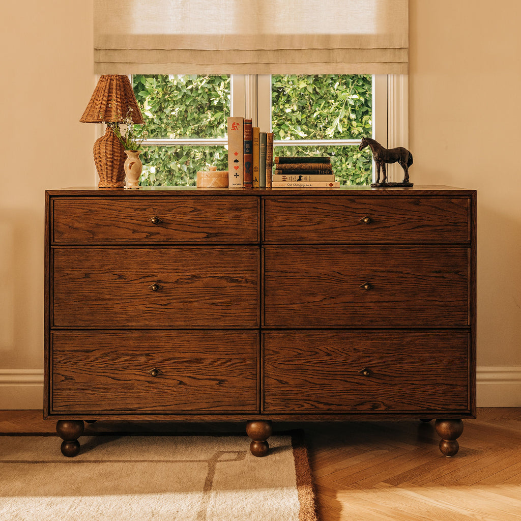 Front view of Astre 6-Drawer Wide Assembled Dresser in Toffee showcasing six drawers and rounded feet in a warm room