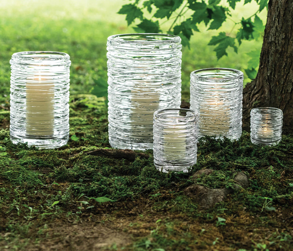 Front view of Echo Lake Hurricane candle holders showcasing handblown ribbed glass texture with lit candles on mossy ground