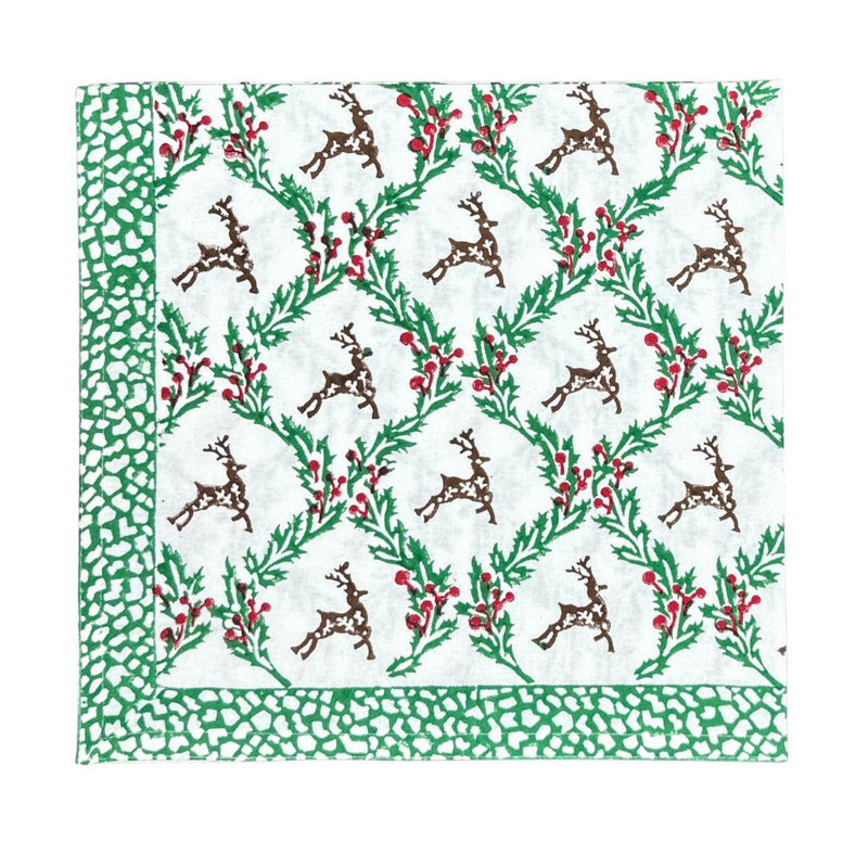 Christmas-themed cloth napkin with reindeer and holly pattern on a white background