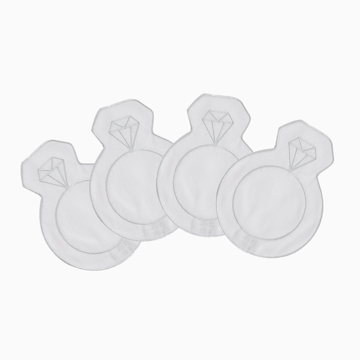 Flat lay of four engagement cocktail napkins shaped like rings, embroidered diamond motif on silver-threaded white linen