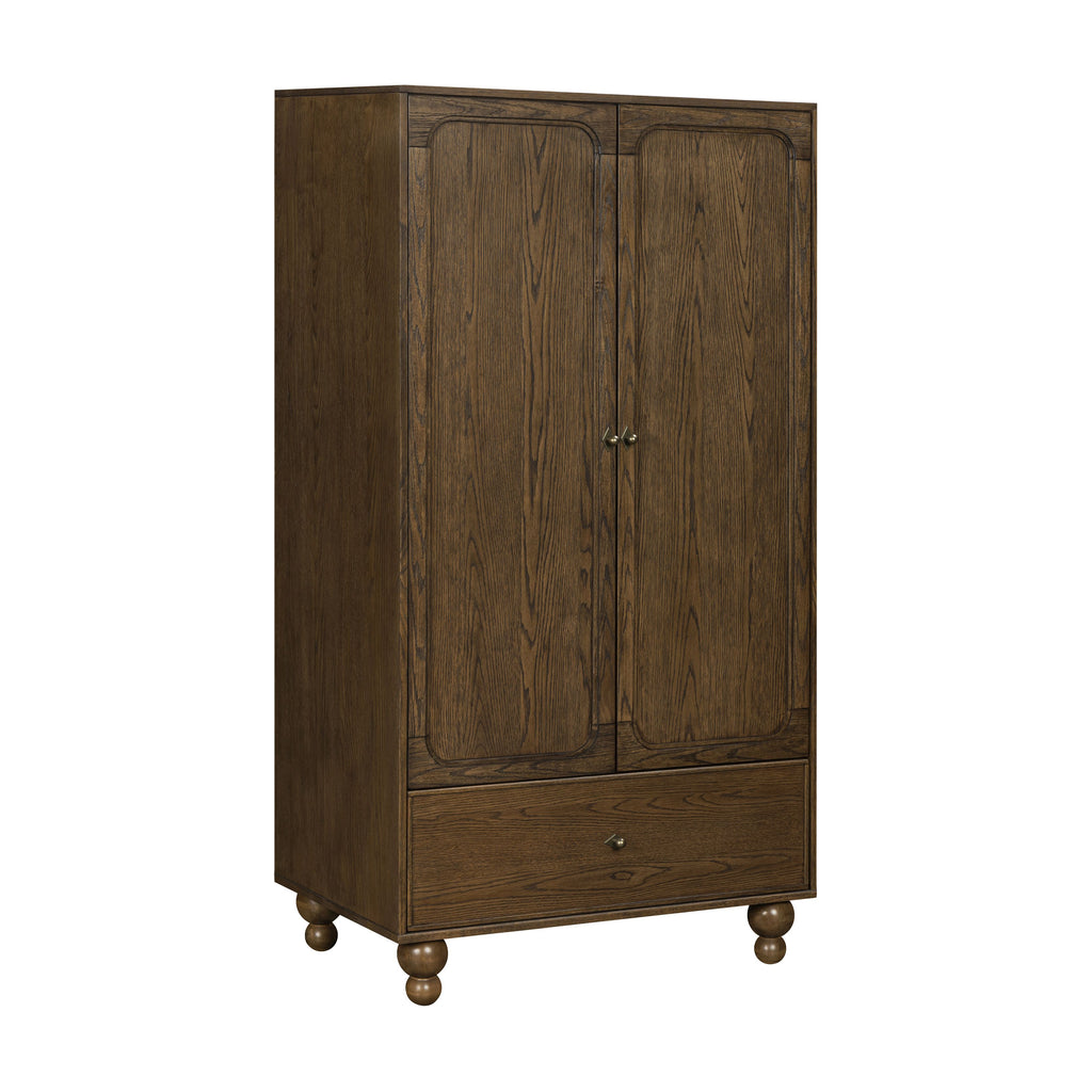 Three-quarter view of Astre Assembled Armoire by Nate Berkus in Toffee with paneled doors, drawer, and turned feet