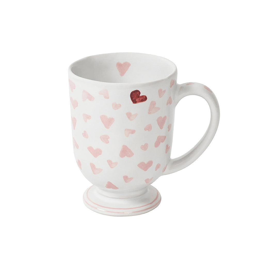 Three-quarter view of Love You More mug with pink heart pattern, red heart accent, and pedestal foot on white background