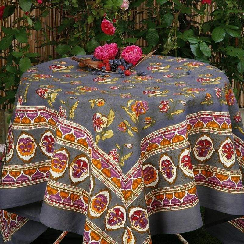 View of French Tablecloth Pansy Red and Grey showcasing floral and abstract patterns on a grey background in a garden setting