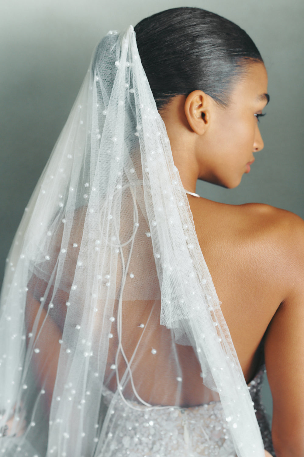Rear view of Perri veil showcasing beaded tulle with scattered acrylic pearls on a gray background
