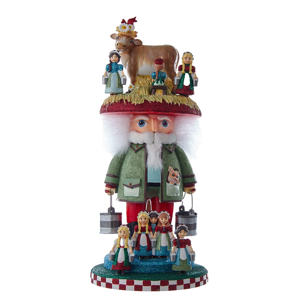 Front view of Hollywood 8 Maids A-Milking nutcracker with eight maids, a cow on its hat, and hanging milk pails on white background