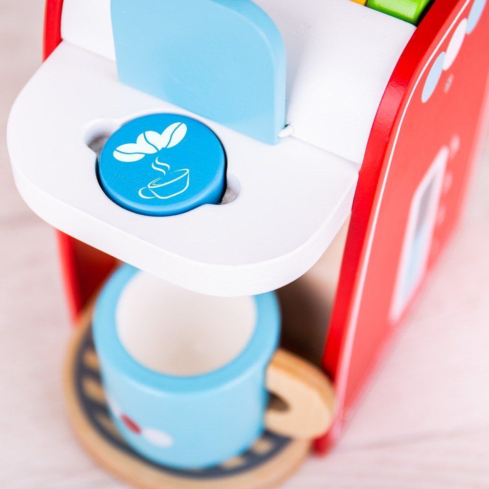 Close-up of wooden kids coffee maker showing blue coffee pod in brew slot and matching mug on a wooden saucer