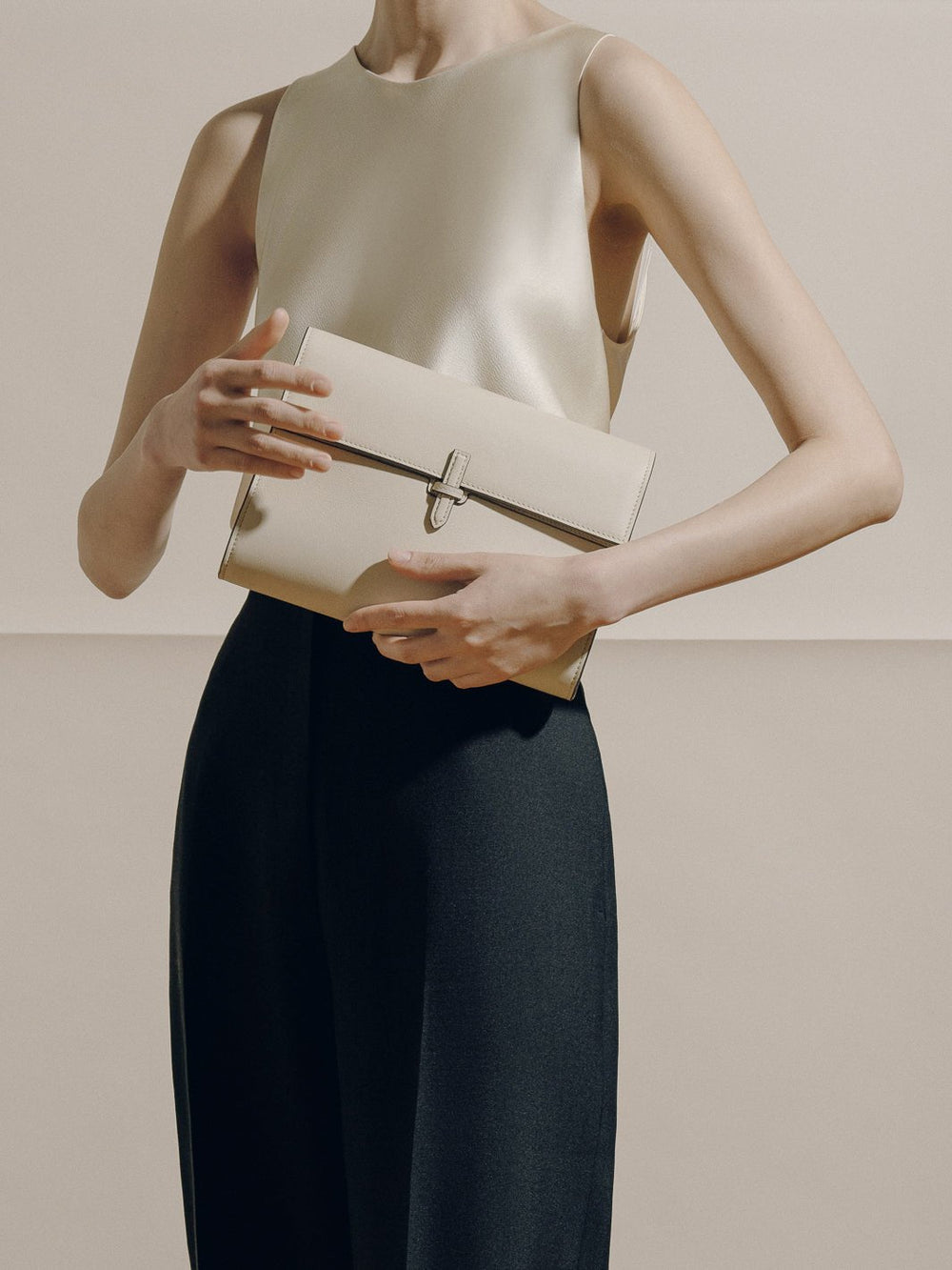 Front view of The Large Soft Clutch in Nappa Oyster showing smooth leather and signature buckle against a neutral studio background