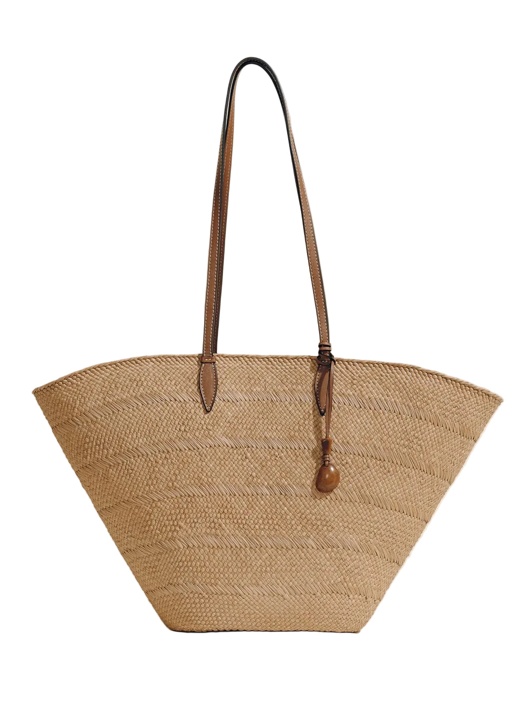 Front view of The Large Trapeze Basket in Nuez Cognac with handwoven iraca body, cognac leather shoulder straps, and tagua charm on white background