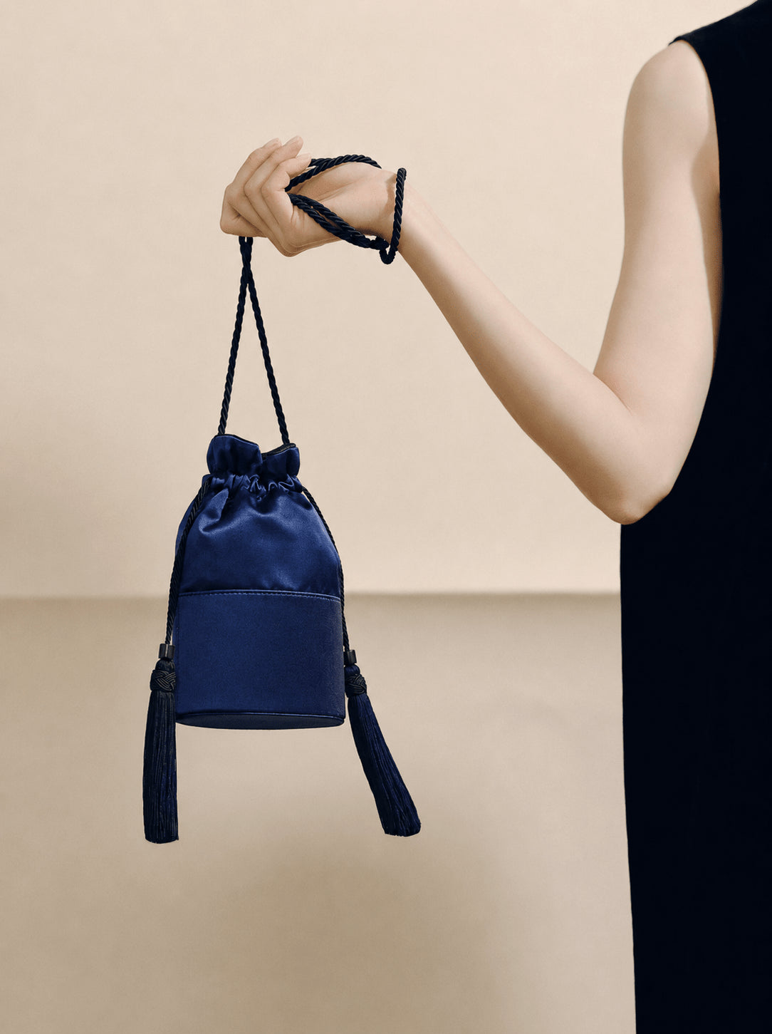 Front view of The Lola in Satin in Navy with a structured base, twisted rope strap, and side tassels