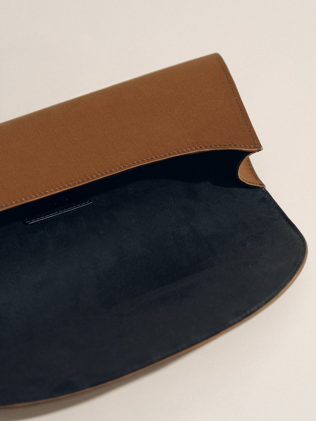 Open view of The Opera Clutch in Dark Brown Satin showcasing its minimalist satin silhouette with a light background