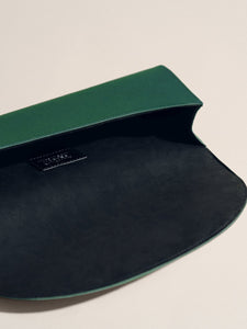 Open view of The Opera Clutch in Emerald Satin showcasing its dark interior and curved flap on a light background