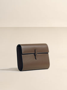 Front view of The Small Soft Clutch in Dark Brown Nappa showcasing its fold-over silhouette and slip-through closure on a light background