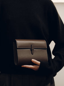 Front view of Small Soft Clutch in dark brown Nappa leather showing fold-over silhouette and slip-through closure