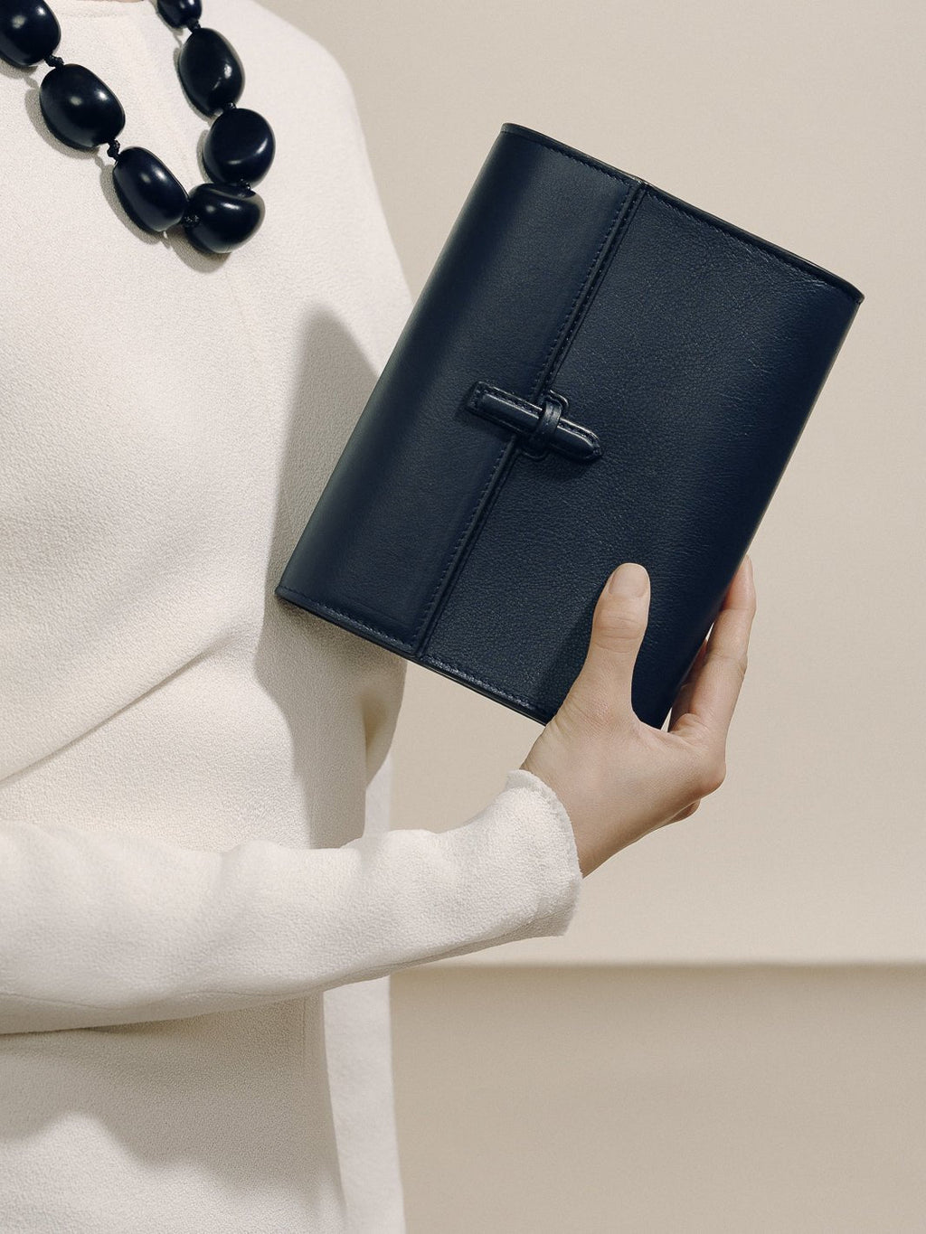 Front view of The Small Soft Clutch in Navy Nappa showcasing its slip-through closure while held against a neutral background