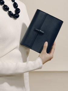 Front view of The Small Soft Clutch in Navy Nappa showcasing its slip-through closure while held against a neutral background