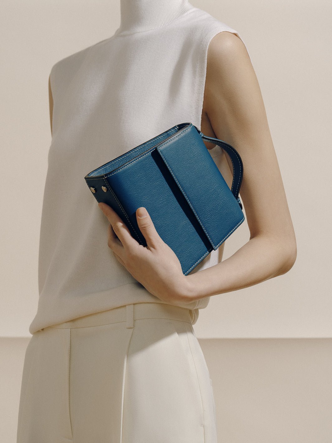 Three-quarter view of The Small Top Handle in Nappa teal showcasing rounded top handle, boxy silhouette, and white topstitching against a neutral studio background