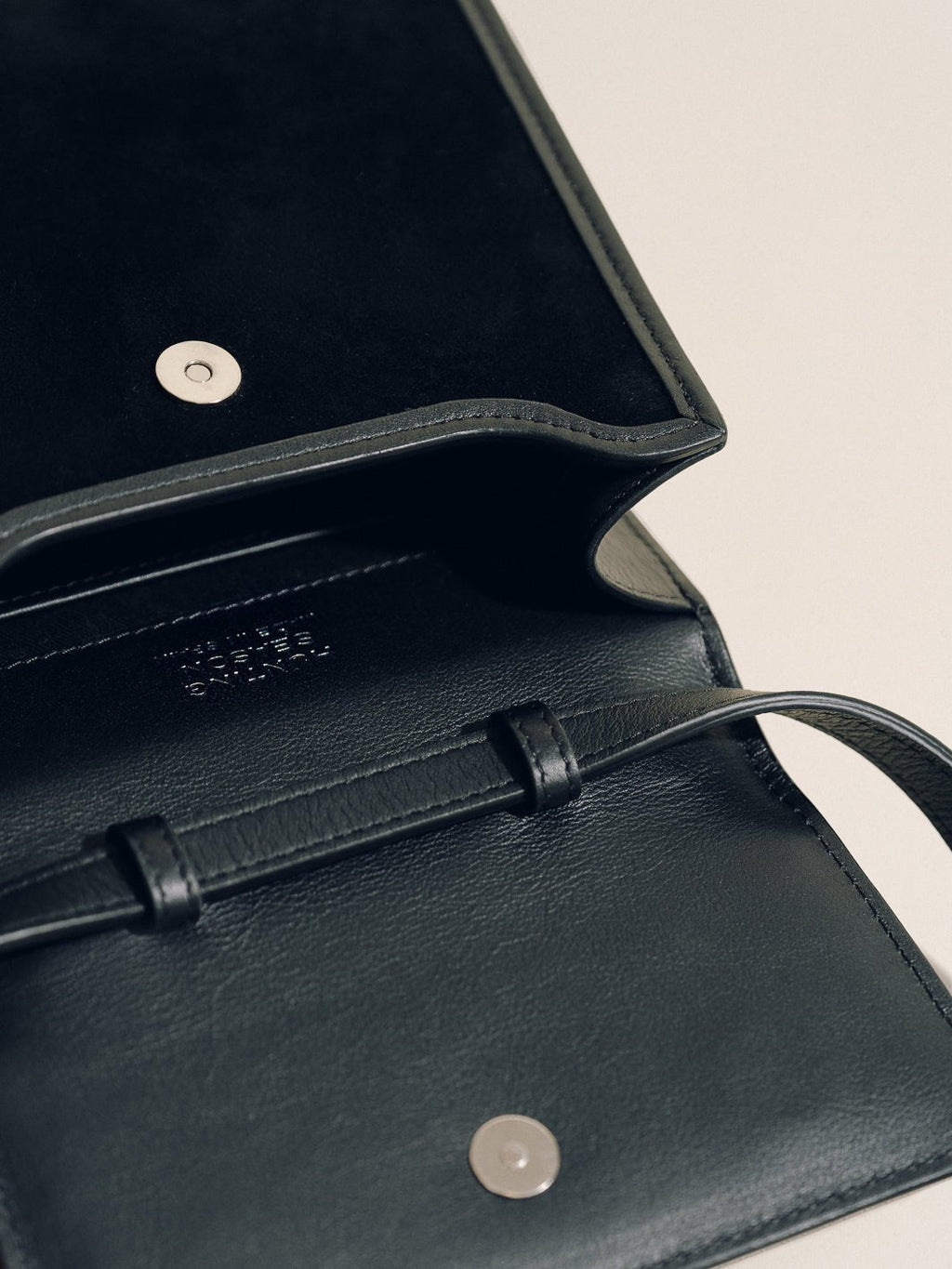 Close-up of The Small Top Handle in black suede showcasing the open interior and magnetic closure