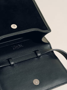Close-up of The Small Top Handle in black suede showcasing the open interior and magnetic closure