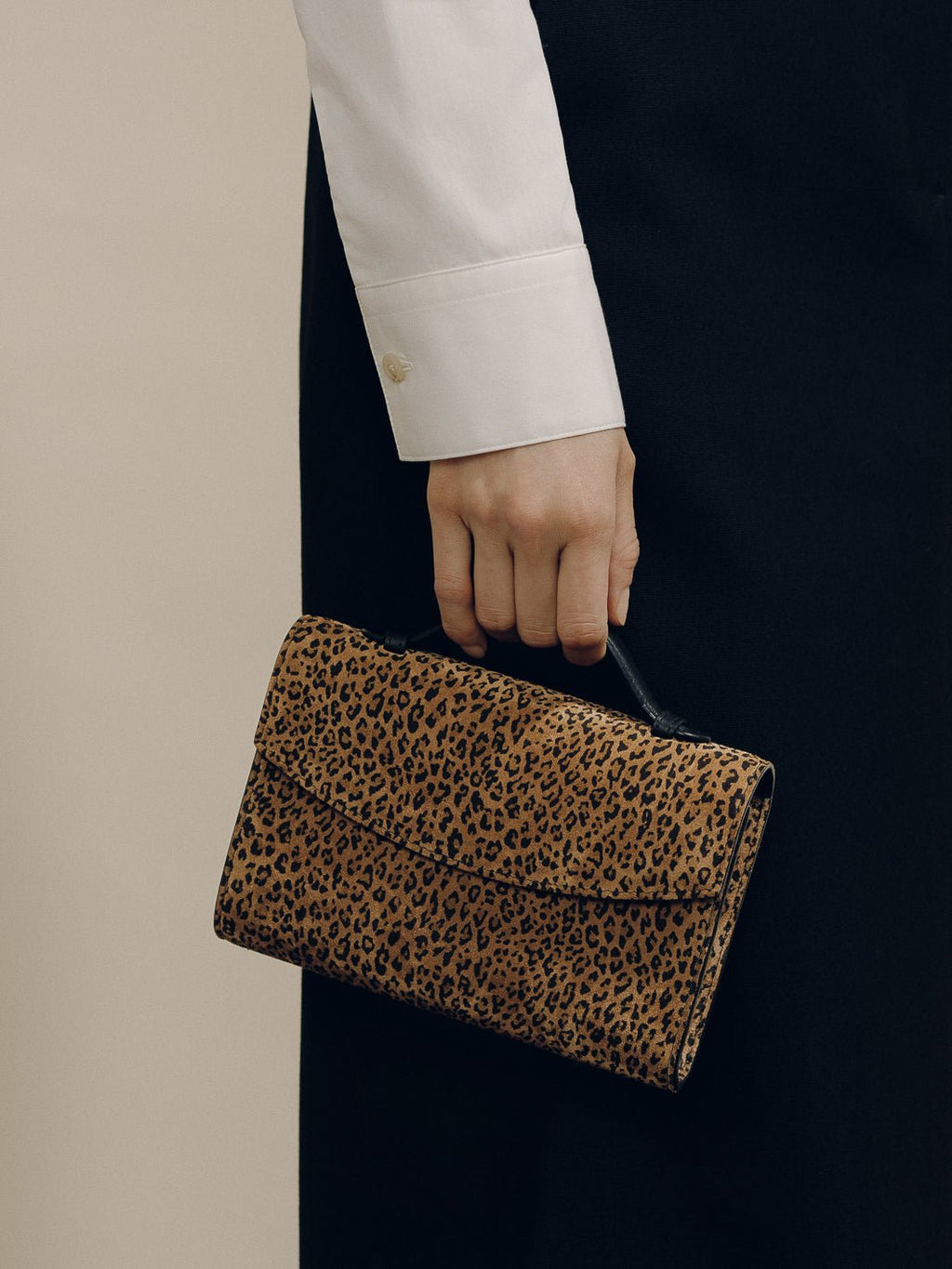 Angled view of the animal print nappa leather top handle clutch showcasing its compact silhouette with a neutral background