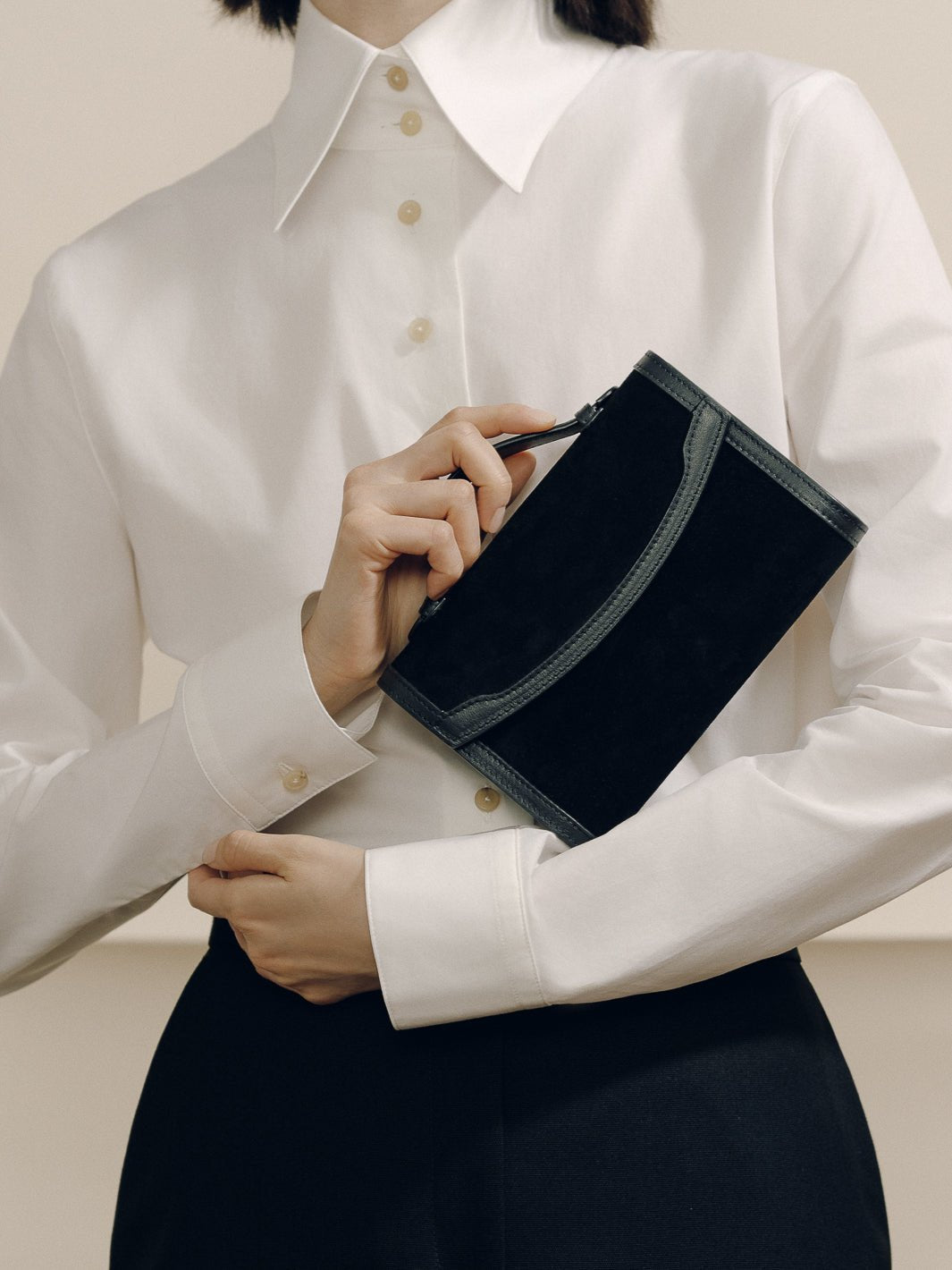 Front view of The Top Handle Clutch in Black with Western Trim showcasing sculpted leather trim against a white blouse