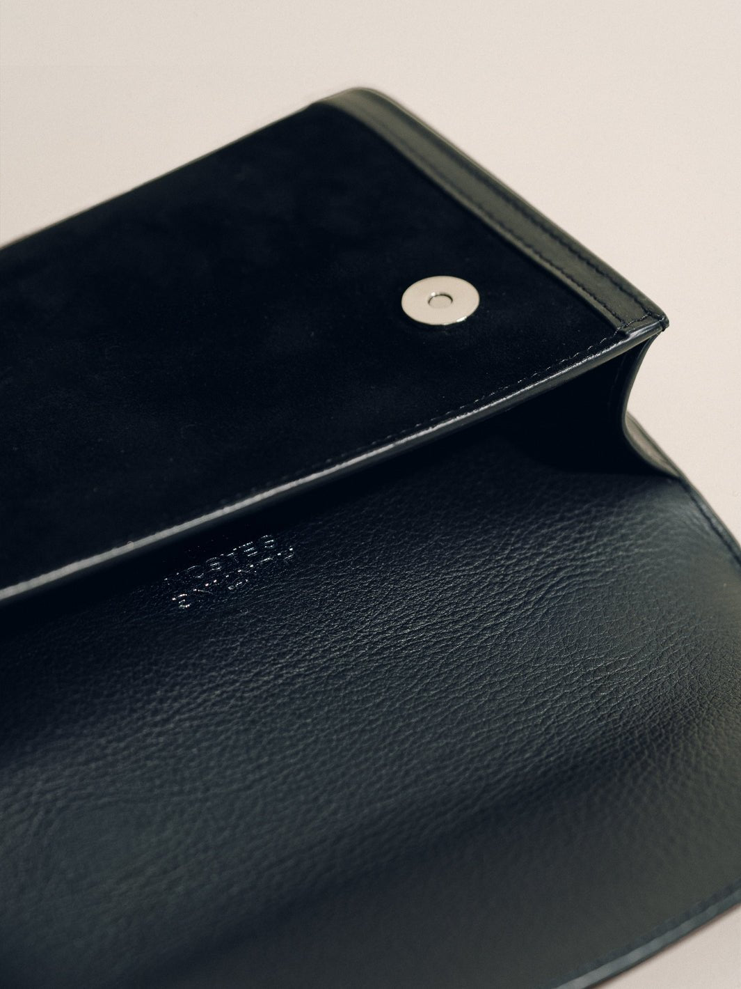 Open view of the black Top Handle Clutch with Western Trim showcasing suede and sculpted leather trim on light background