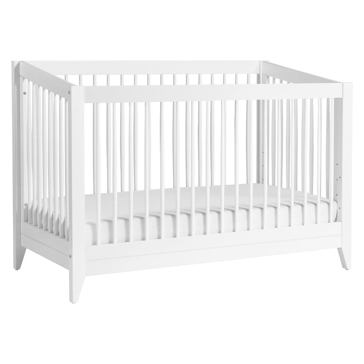 Three-quarter view of white Sprout 4-in-1 convertible crib showcasing tapered spindles and triangular feet, white backdrop