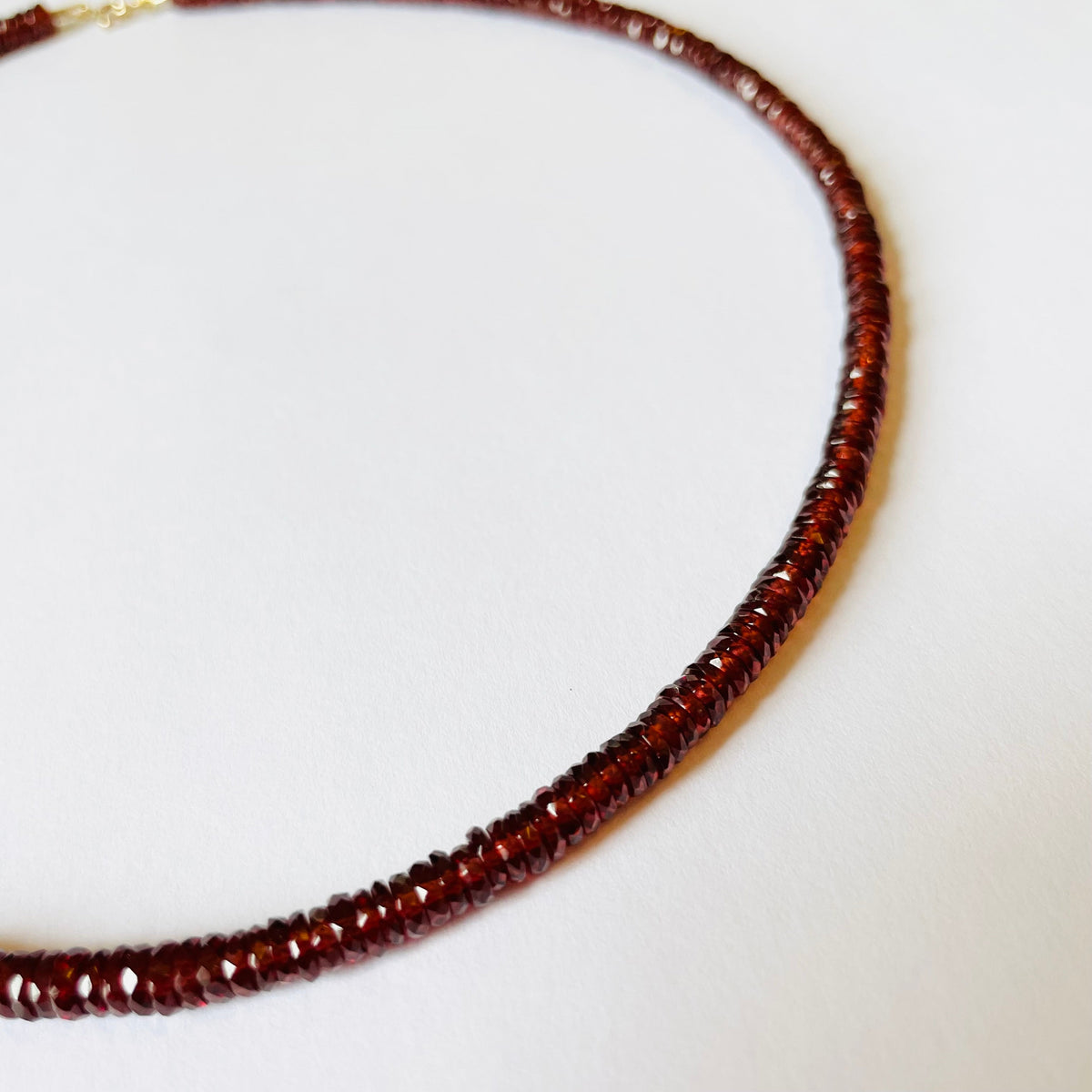 Close-up of Garnet Heishi Necklace showcasing richly hued garnet heishi beads with a white background