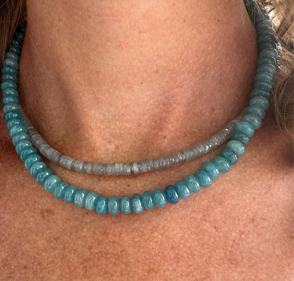 Close up of Peacock Blue Angelite Candy Necklace layered with faceted pale grey beads worn on a model’s neck