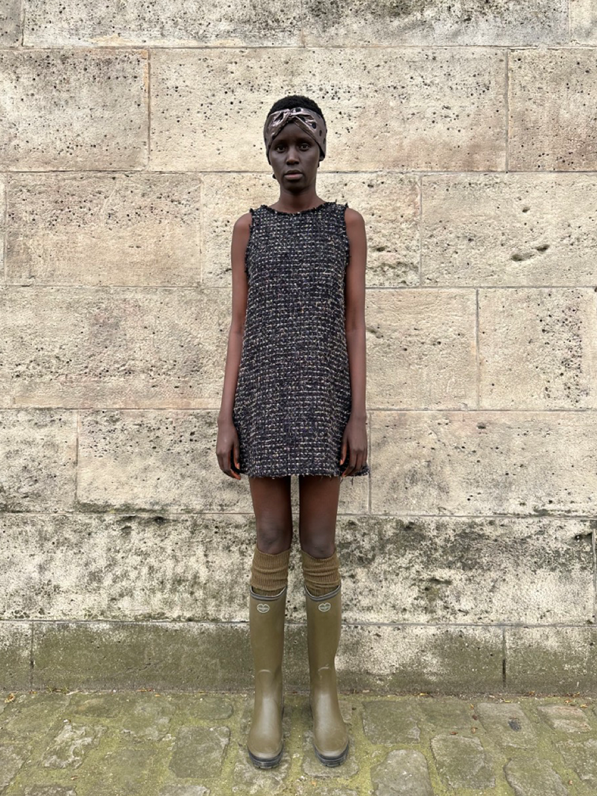 Front view of Jane Dress in Arc en Ciel tweed showcasing sleeveless A-line silhouette and raw edges against a stone wall