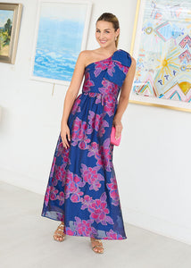 Woman wearing a blue floral one-shoulder dress in an art gallery setting.
