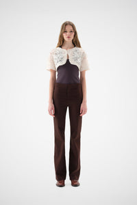 Cream lace bolero with floral rose embroidery, short-sleeve cropped fit, worn over a dark top and brown trousers.