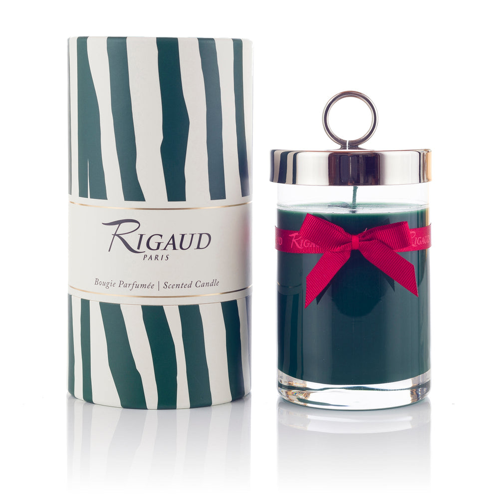 Front view of Rigaud Cyprès scented candle in clear jar with silver lid and red ribbon beside striped gift box labeled Rigaud Paris
