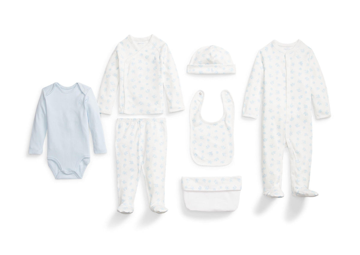 Flat lay of Organic Cotton 7-Piece Gift Set showcasing baby clothing, hat, bib, and storage pouch on a white background