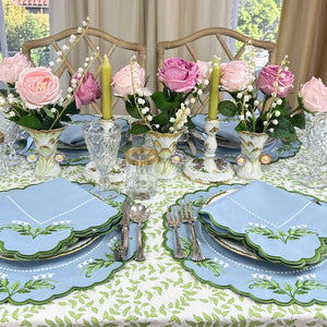 table setting with floral centerpieces, plates, and cutlery on a patterned tablecloth. Luxury Lilly of the valley embroidered placemats and napkins