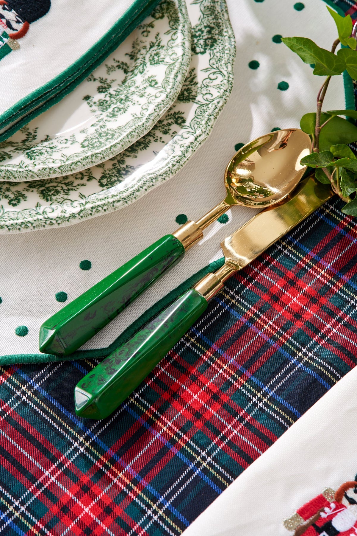 Close-up of Malachite Cutlery showcasing green resin handles and gold-colored stainless steel with patterned table linens