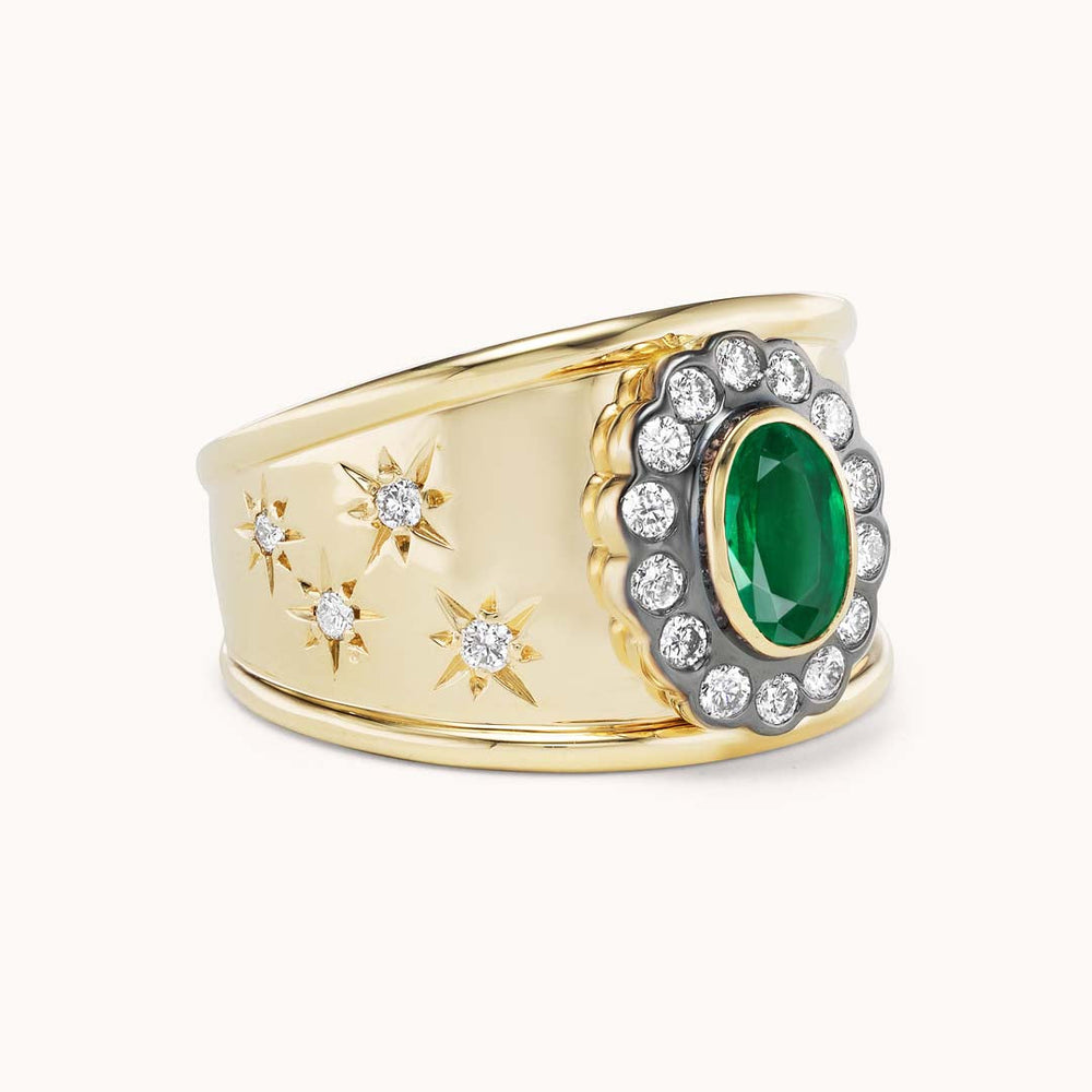 Angled view of Ali Cigar Band ring showing oval emerald, diamond halo, and star-engraved yellow-gold band on white background