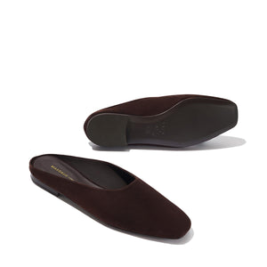 The Clara - Espresso Suede by Margaux: dark brown suede slip-ons with a slipper-like silhouette, squared toes, flat soles, and a minimalist design. One shoe is upright; the other lies on its side to show the sole.