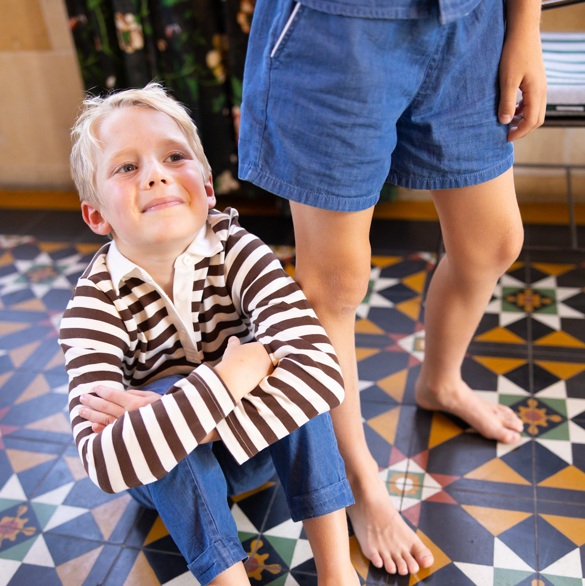 Front view of boys’ chambray drawstring shorts worn by child showcasing cuffed hem and side pockets on patterned tile floor