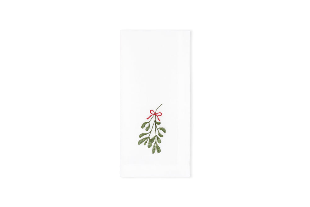 Flat-lay of Mistletoe napkin showcasing embroidered mistletoe sprig with red bow on white background