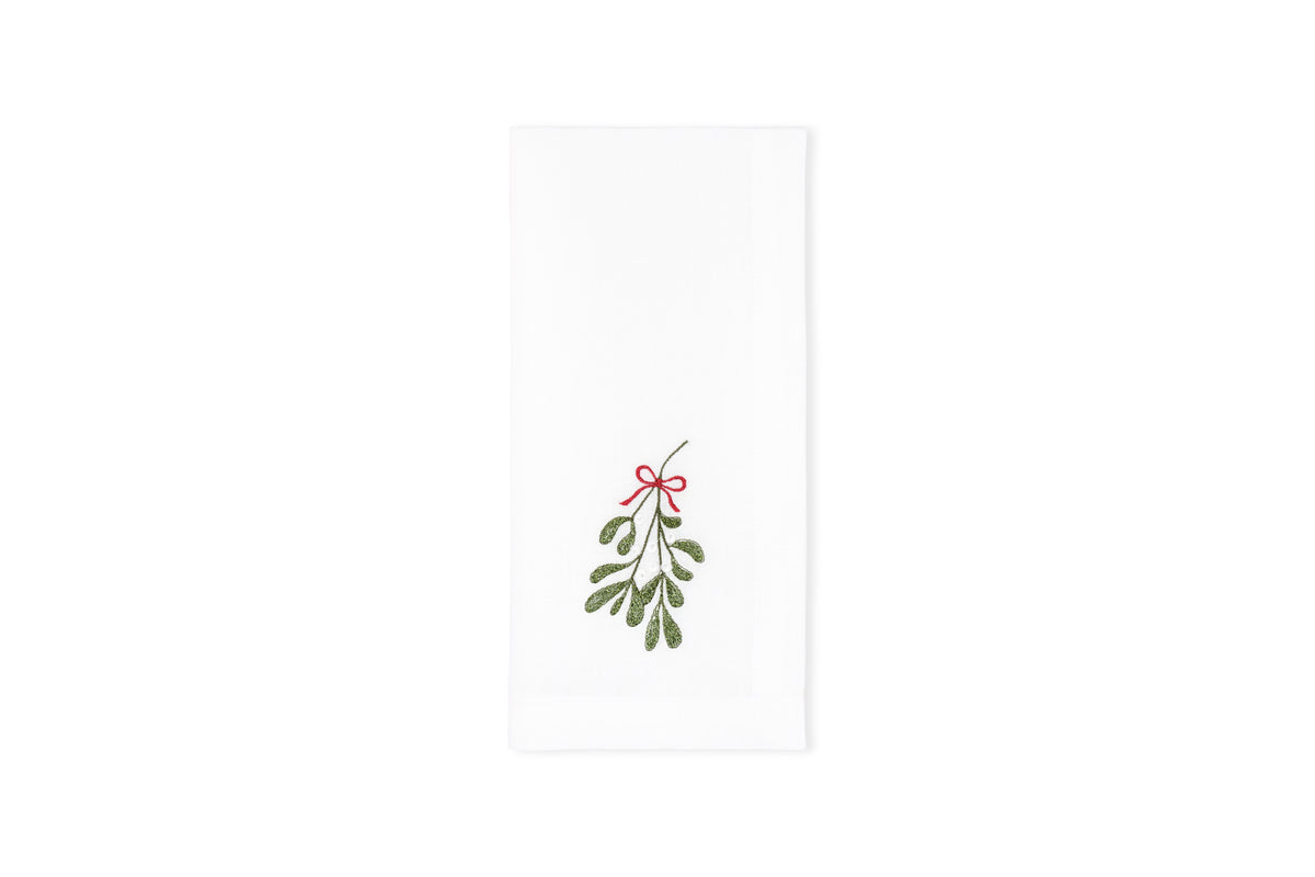 Flat-lay of Mistletoe napkin showcasing embroidered mistletoe sprig with red bow on white background