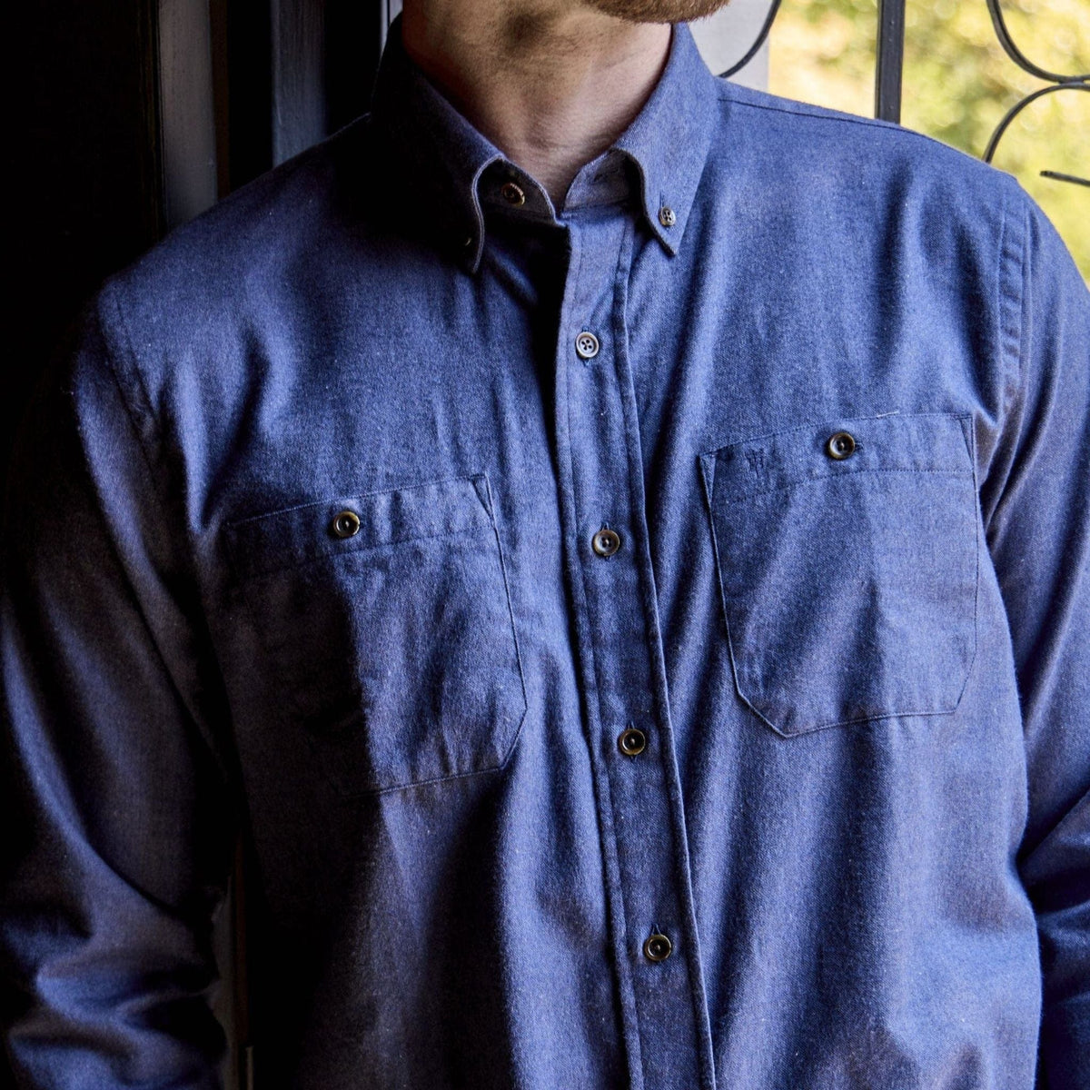 Man wearing the Tom Beckbe Dixon Brushed Cotton Twill Shirt with chest pockets, standing by a sunlit window.