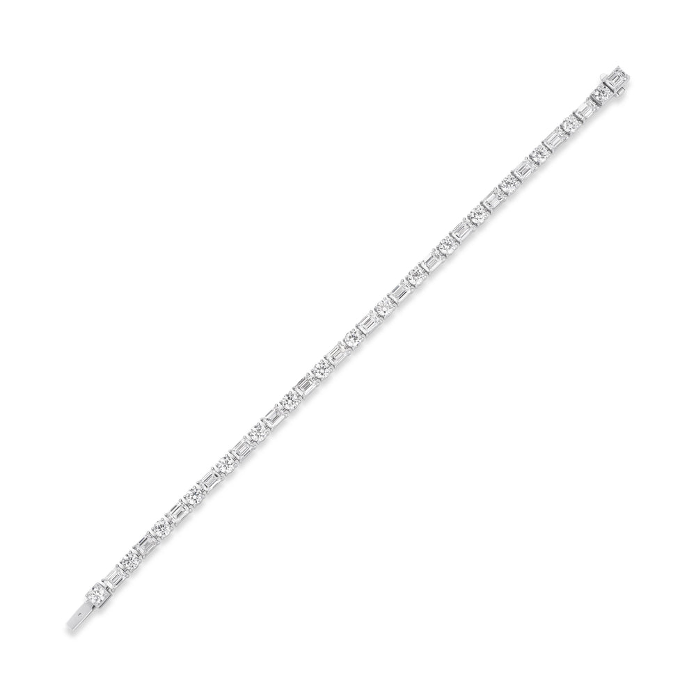 An Alternating East-West Set Round and Emerald Cut Diamond Tennis Bracelet in white gold, featuring sparkling diamonds set in a unique east-west pattern, elegantly displayed diagonally on a white background.